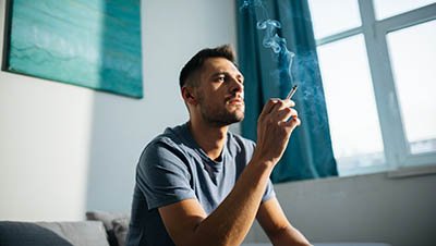 Мужчина сидит с сигаретой на диване