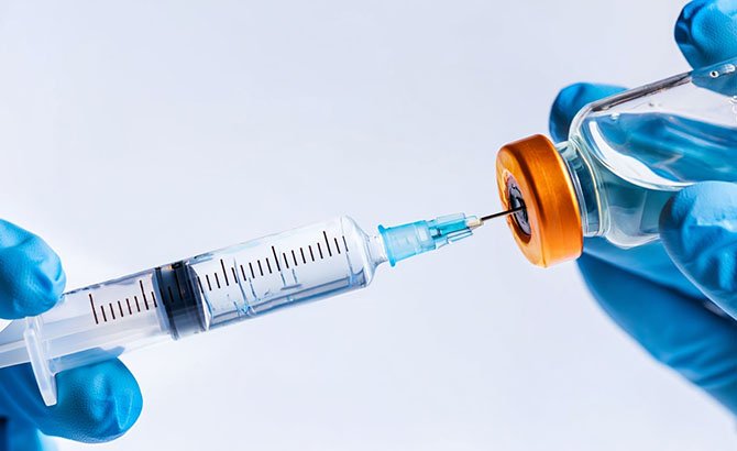 Врач набирает из стеклянного флакона лекарство